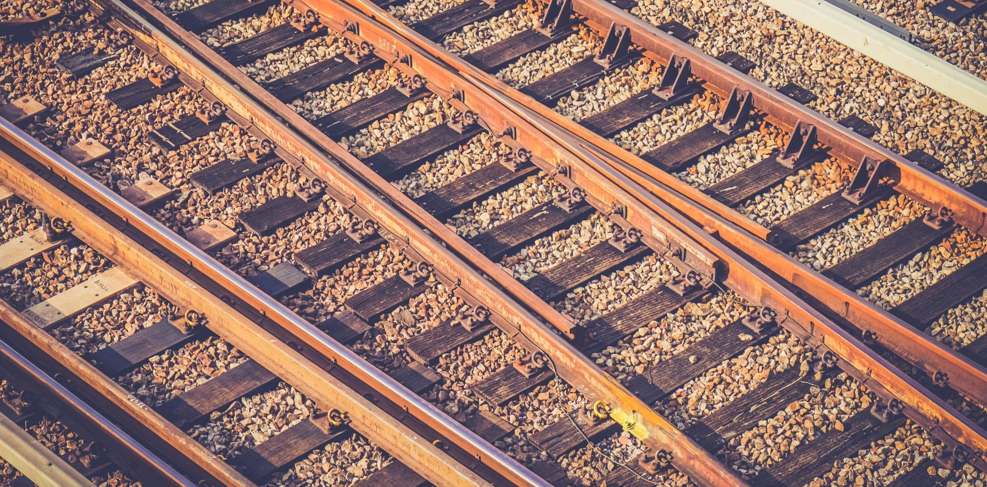 Rusty-hued closeup photograph of tracks running through a train yard
